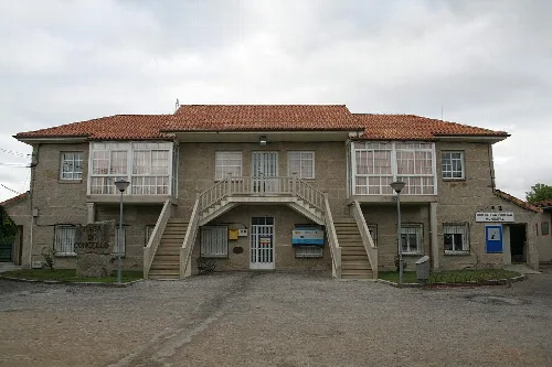 Zweistöckiges Gebäude mit Treppen und großen Fenstern an der Fassade.