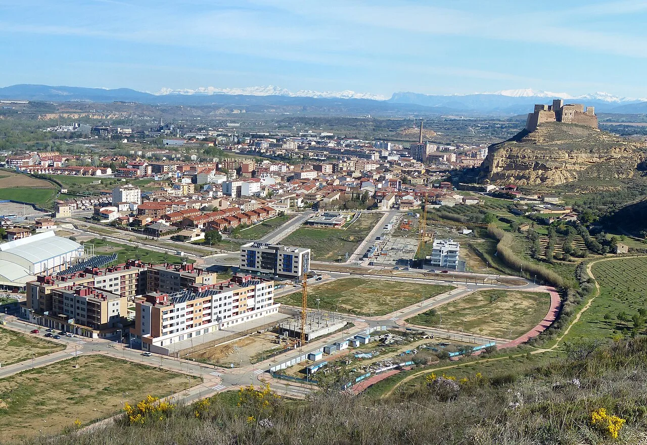 Blick auf Monzón, mit der Burg auf dem Hügel und modernen Gebäuden im Tal.