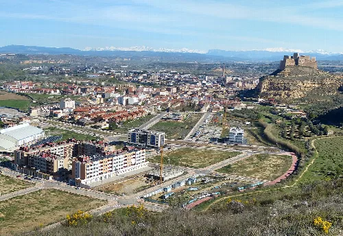 Blick auf Monzón, mit der Burg auf dem Hügel und modernen Gebäuden im Tal.