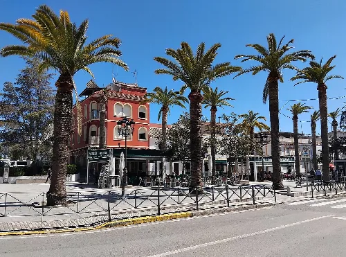 Palmen und rotes Gebäude am Paseo Diego Carro, Nueva Carteya.