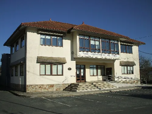 Weißes Gebäude mit großen Fenstern und rotem Ziegeldach.