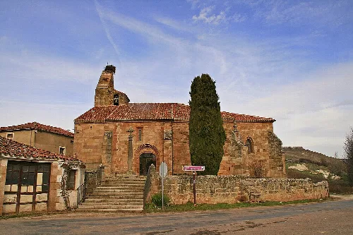 Santa Cecilia church with stone facade and tall tree in Salas de los Infantes.