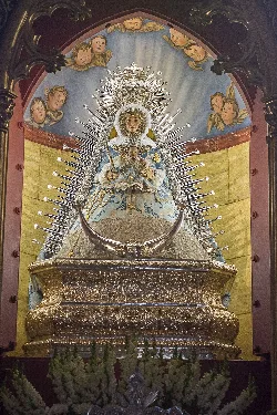 Statue der Virgen de Setefilla mit Krone und prunkvoller Kleidung auf einem Altar.