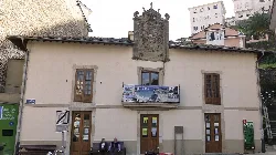 Two-story building with wooden doors and windows, and a sign on the facade.