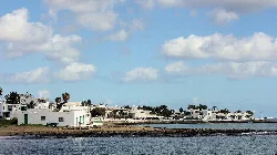 Coast with white houses, palm trees, and sea at Playa Honda, San Bartolomé.