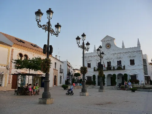 Plaza del Ayuntamiento de Cartaya con iglesia blanca y farolas antiguas.