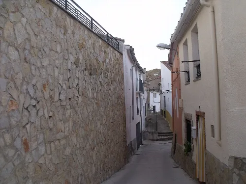 Streets of the town with white houses and stone wall.
