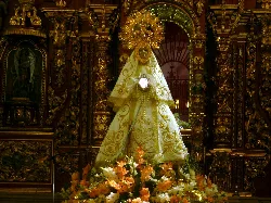 Statue von Nuestra Señora de las Cruces auf einem Altar mit Blumen und goldener Dekoration.