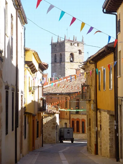 Narrow street with banners and church tower in the background
