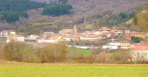 Panoramablick auf Bernedo mit Häusern, Kirche und Hügeln im Hintergrund.