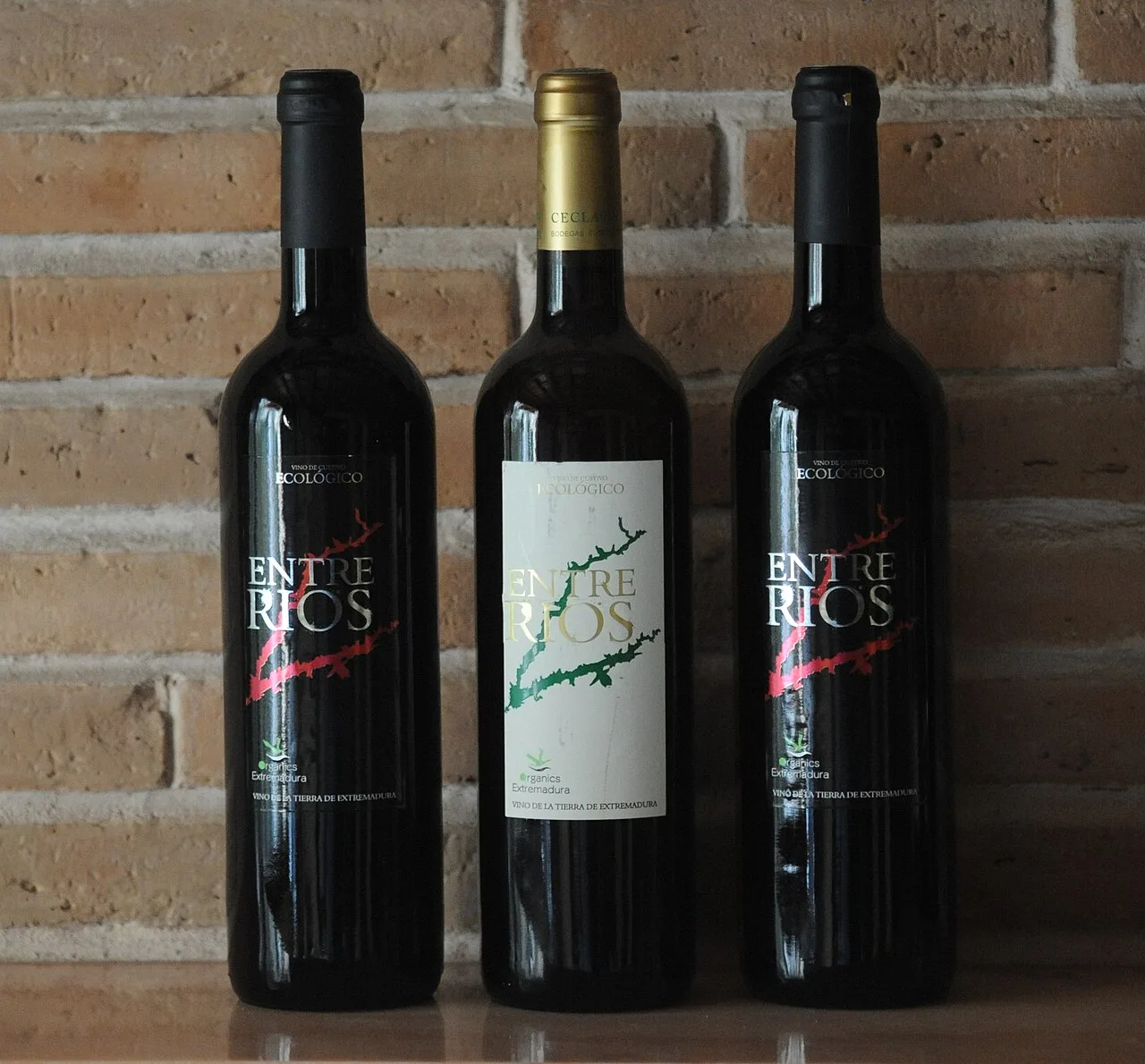 Three bottles of Ceclavín's pitarra wine on a wooden surface.