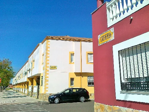 Gebäude mit einem Schild 'Corte de Peleas' und eine Straße mit einem geparkten Auto.