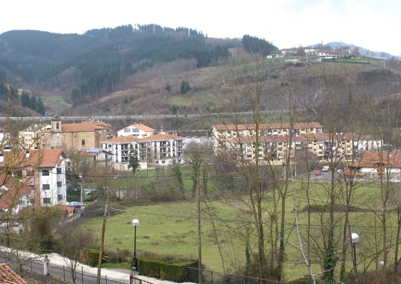 Houses and buildings in a valley surrounded by hills and bare trees in Ormaiztegi.