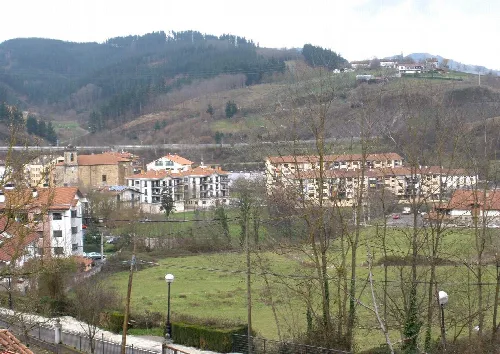 Häuser und Gebäude in einem Tal, umgeben von Hügeln und kahlen Bäumen in Ormaiztegi.