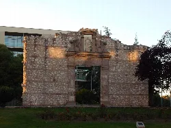 Restos de una estructura antigua con puerta y detalles religiosos
