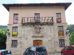 Edificio del ayuntamiento con escudo y banderas en la fachada.
