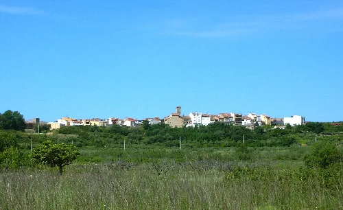 View of a tower in a village with white houses and a blue sky.
