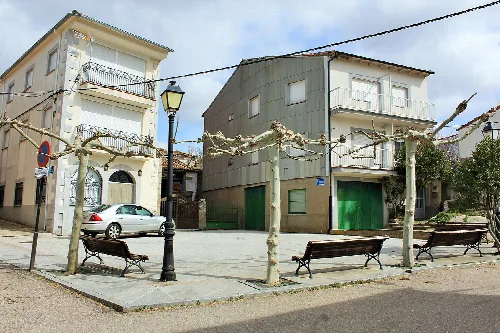 Main square with benches, lampposts, and decorative trees in Fresnedoso.