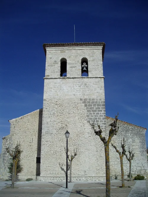Iglesia de La Parrilla con torre y árboles en primer plano.