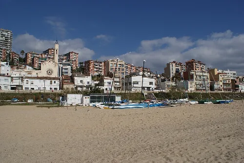 Blick auf den Strand von Montgat mit Gebäuden und Booten.