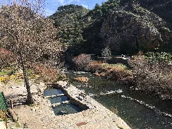 Thermalwasserbecken neben einem Fluss in einer bergigen Landschaft.