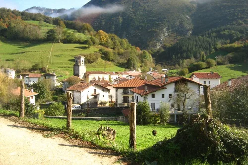 Pueblo con casas blancas y tejados de teja en un valle rodeado de montañas.