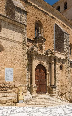 Church facade with arched entrance, columns, and a memorial plaque.