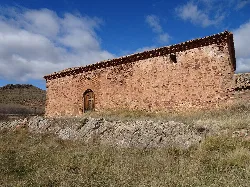 Vista del lado sur de la ermita, con puerta de madera y pequeño ventanuco.