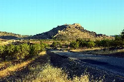 View of Moya hill with ancient structures and vegetation in the foreground.