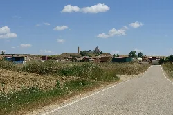 Camino rural con casas y una iglesia en el fondo en Lomas de Campos, Palencia.