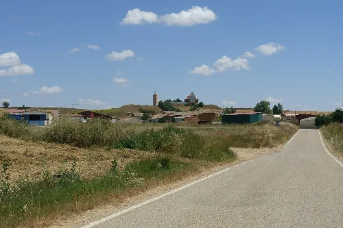 Rural road with houses and a church in the background in Lomas de Campos, Palencia.