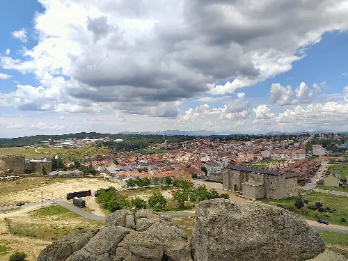 Blick auf Häuser und eine Burg in Las Navas del Marqués bei bewölktem Himmel.