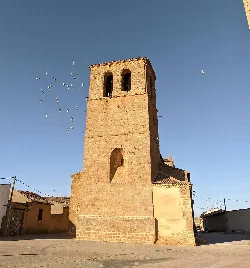 Torre de piedra de la iglesia con palomas en el cielo azul.