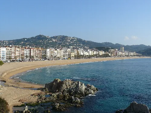 Blick auf den Strand von Lloret de Mar mit Gebäuden und Hügeln.