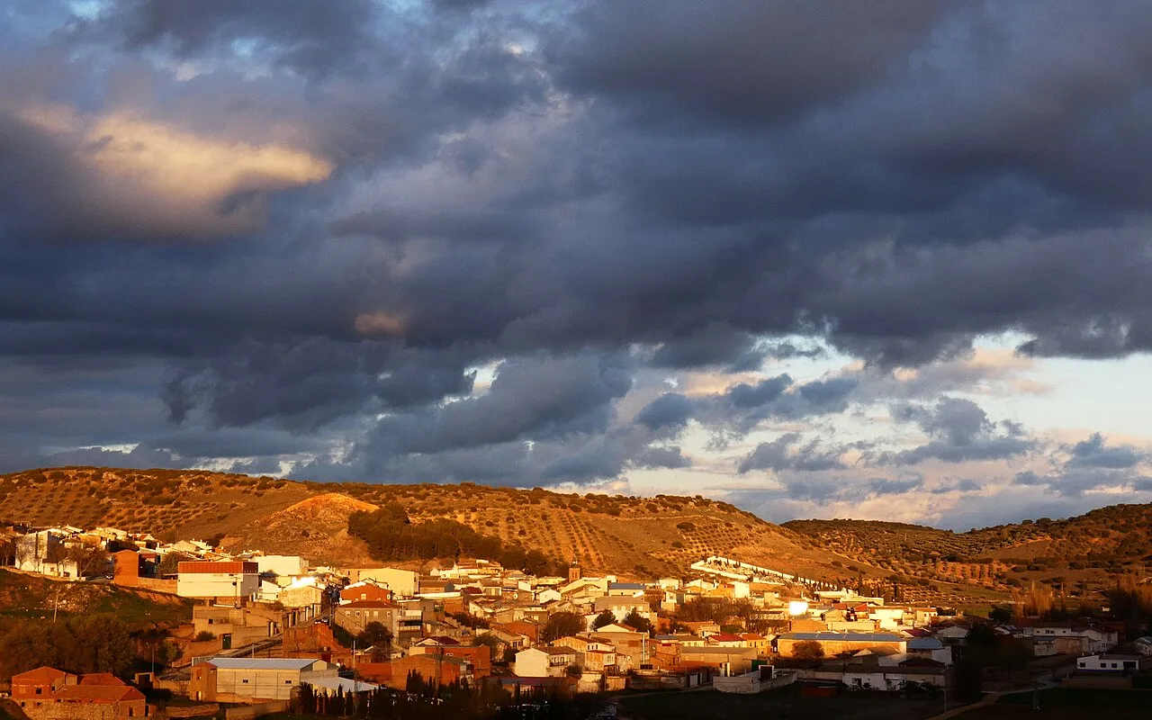 Paisaje de Carrizosa con nubes oscuras y cielo despejado.