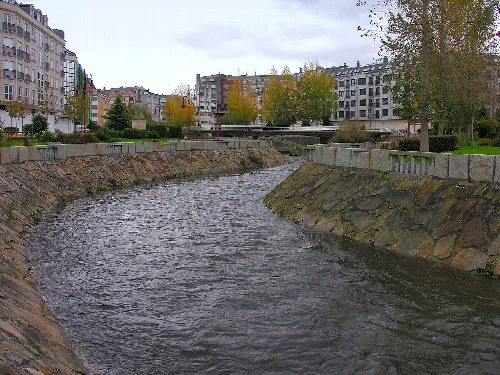 Anllóns Fluss mit Bäumen und Gebäuden im Hintergrund in Carballo.