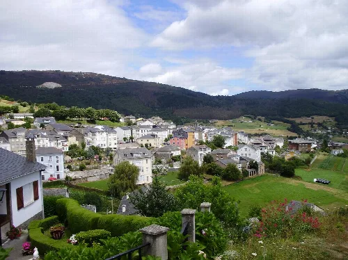 Vista de casas blancas y verdes en un valle rodeado de montañas en Asturias.