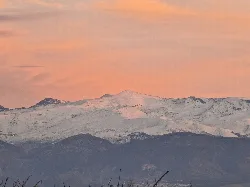 Schneebedeckte Sierra Nevada Berge bei orangefarbenem Himmel.
