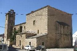 Iglesia en Navas del Madroño con torre y fachada de piedra.