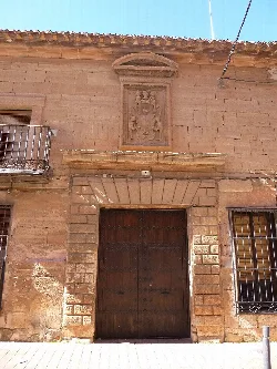 Stone house facade with wooden door and heraldic shield above.