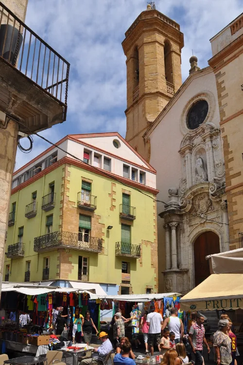 Marktstände und Menschen auf dem Platz mit Santa Maria Kirche und Gebäuden.