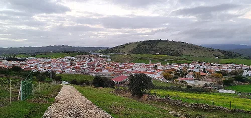 Blick auf eine Stadt mit weißen Häusern und grünen Hügeln im Hintergrund.