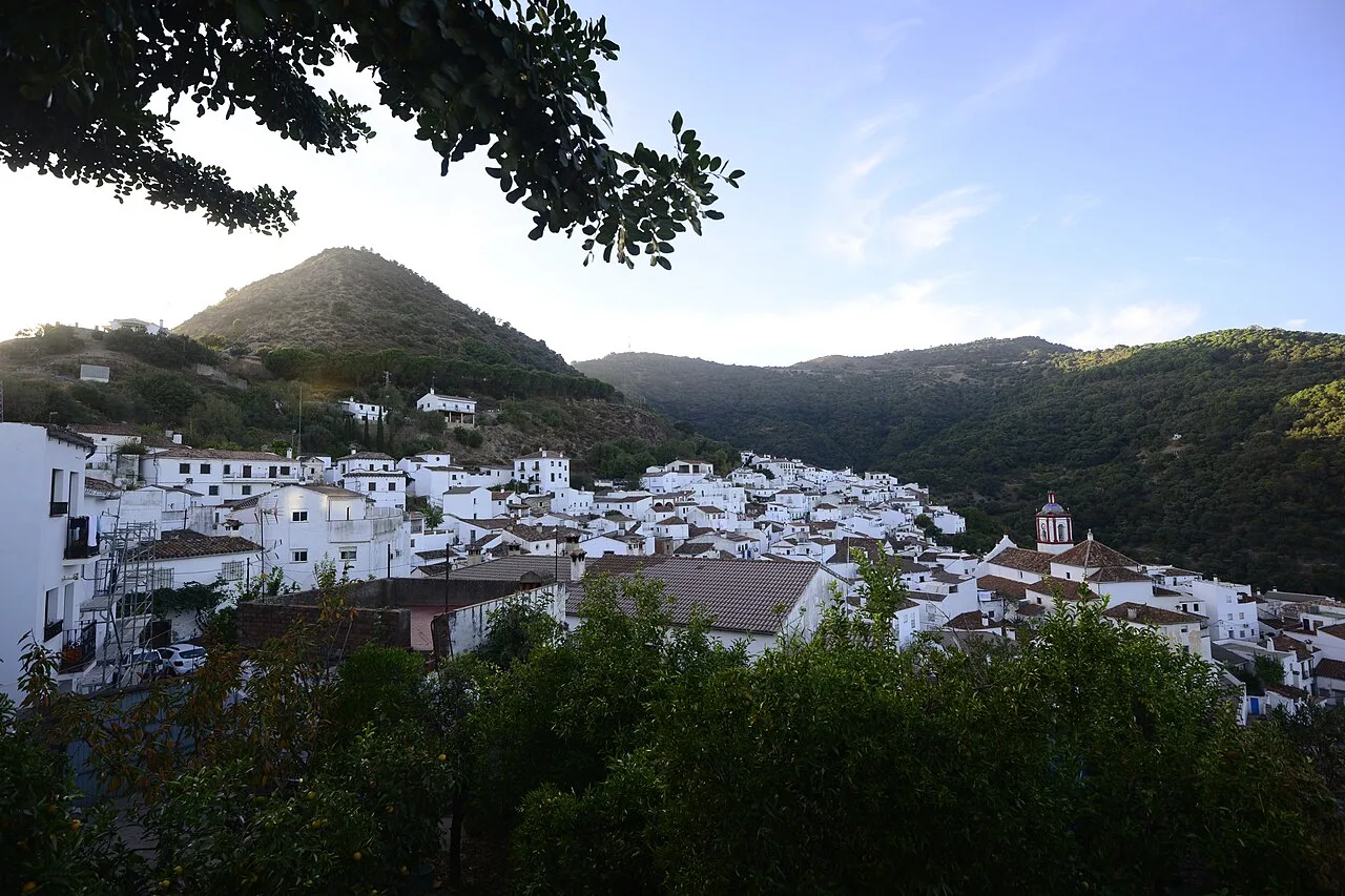 Panoramic view of a white village in the hills with mountains in the background.