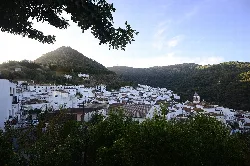 Vista panorámica de un pueblo blanco en las colinas con montañas al fondo.