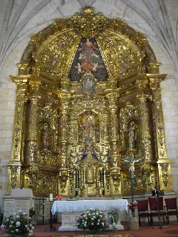 Golden altarpiece with religious figures in Canicosa de la Sierra church.