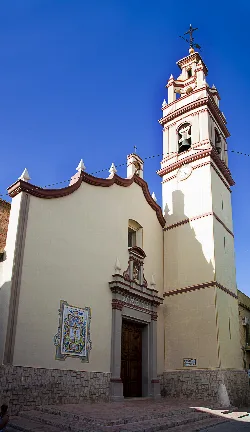 Facade of the church with bell tower and red details in Massanassa.