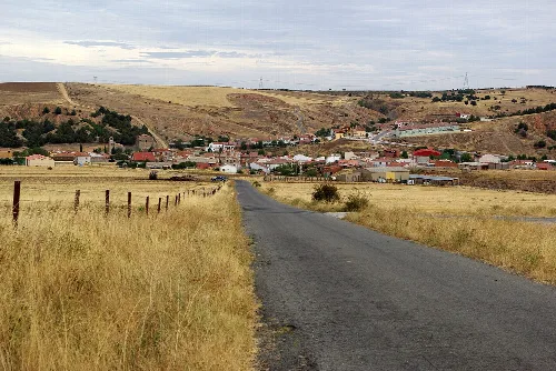 Asphaltstraße in offener Landschaft mit Dorf in der Ferne.