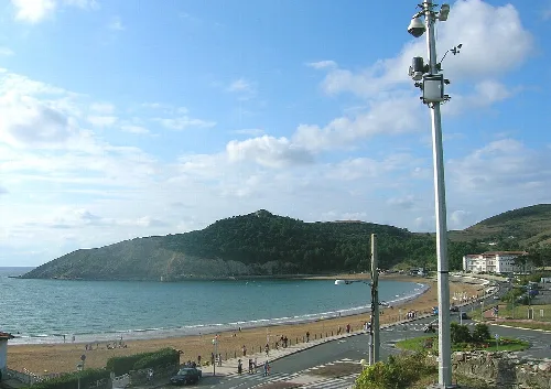 Vista de la playa de Gorliz y Astondo con cielo nublado y gente en la arena.
