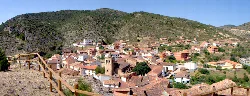 Vista de El Cuervo con casas, montañas y campanario en el centro.