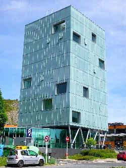 Edificio de vidrio en Behobia, Irún, con pilares inclinados en la base.